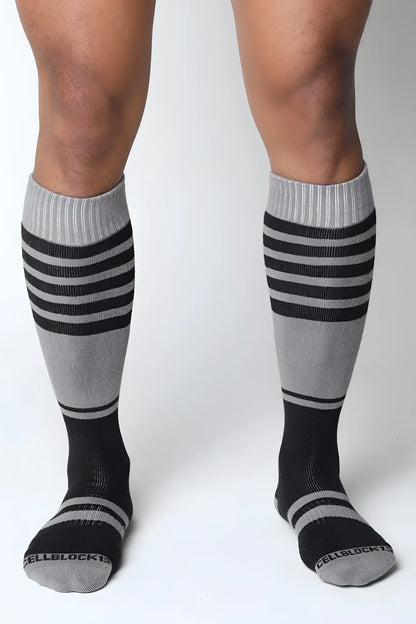 Gray and black striped midfield knee high socks with ribbed cuff and cellblock brand name on the toe
