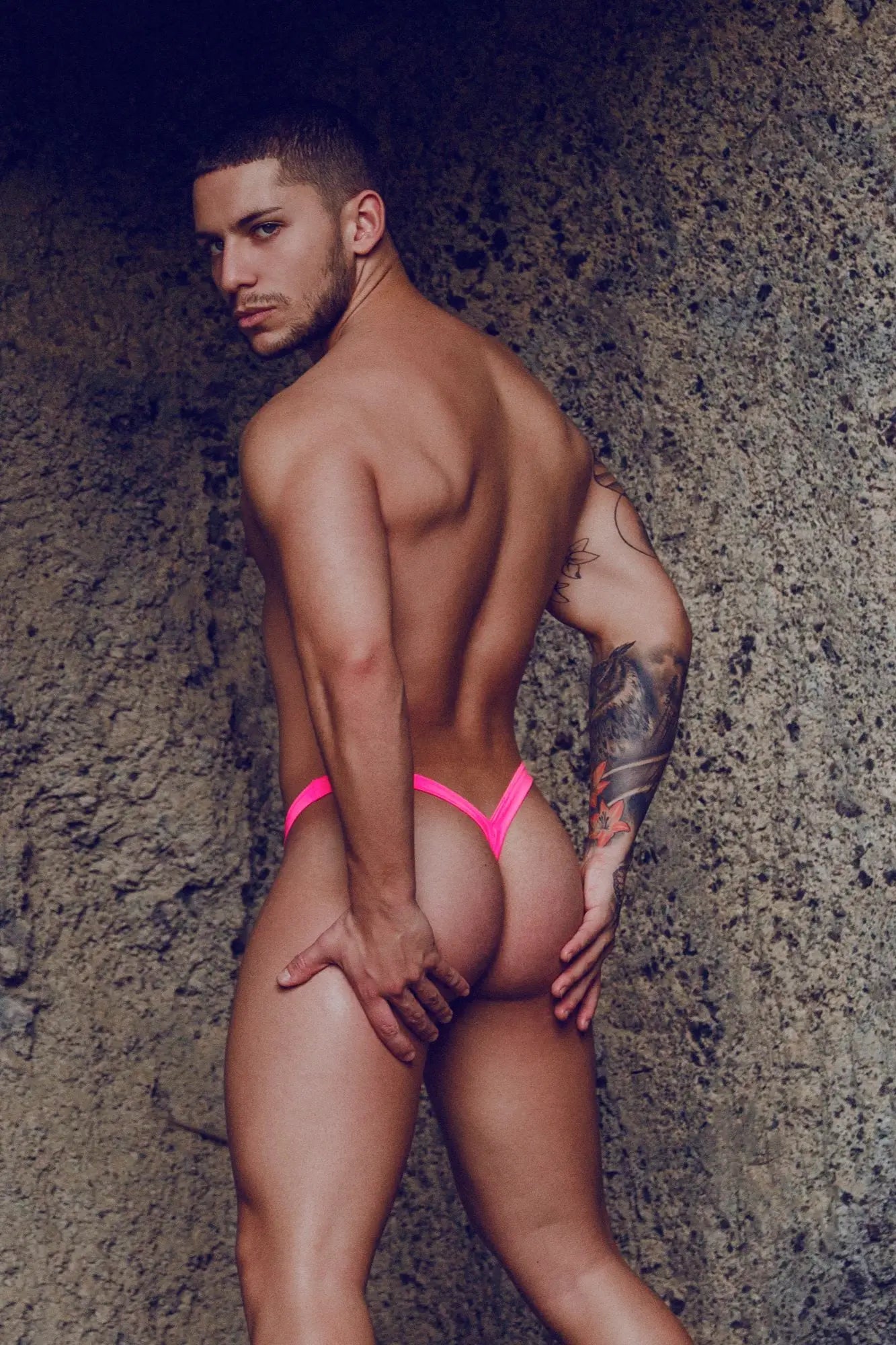 Bright pink thin-strapped mob y buns thong worn by a man showing the front side