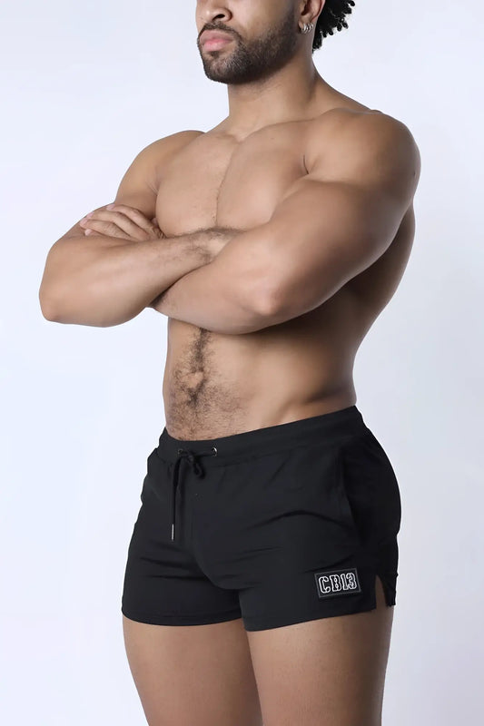 Black muzzle up athletic shorts with drawstring waistband and small rectangular logo patch on lower left leg