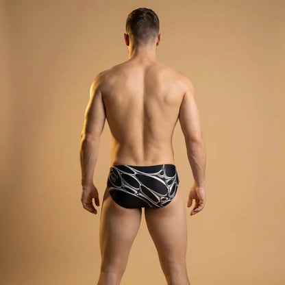 Black briefs featuring a silver 3D liquid metal chrome graphic pattern on a muscular model from the back.