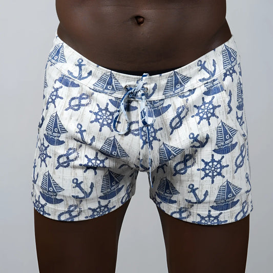 White linen texture shorts with blue nautical pattern of anchors sailboats and ship wheels in swim trunks style