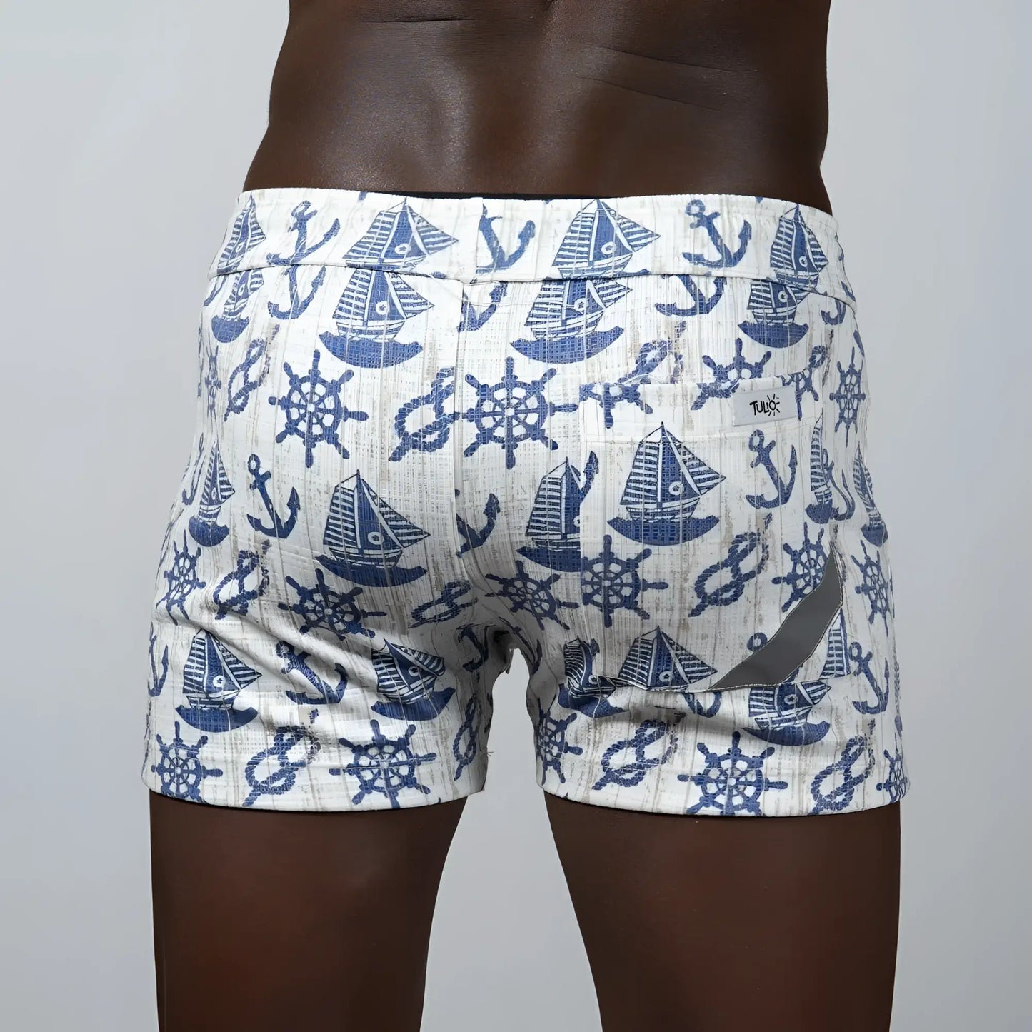 White nautical linen texture shorts featuring a navy blue pattern of sailboats anchors and ship wheels