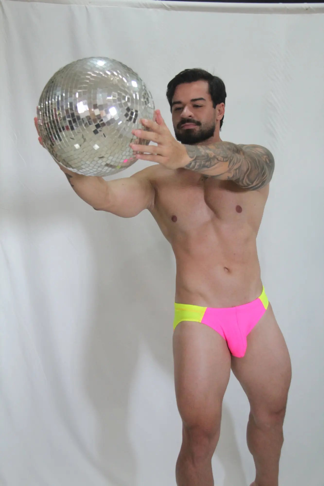 Shiny silver disco ball with mirrored facets reflecting light for neon curved swim brief product display