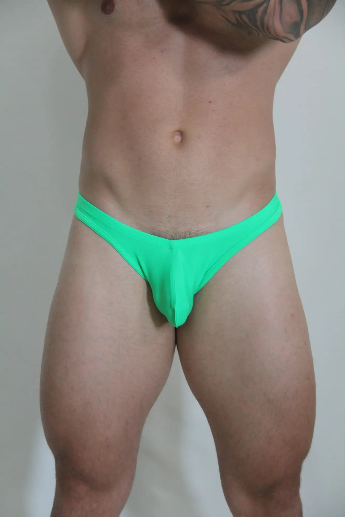 Bright green neon swim thong made of smooth fabric with a form-fitting design shown from the back side
