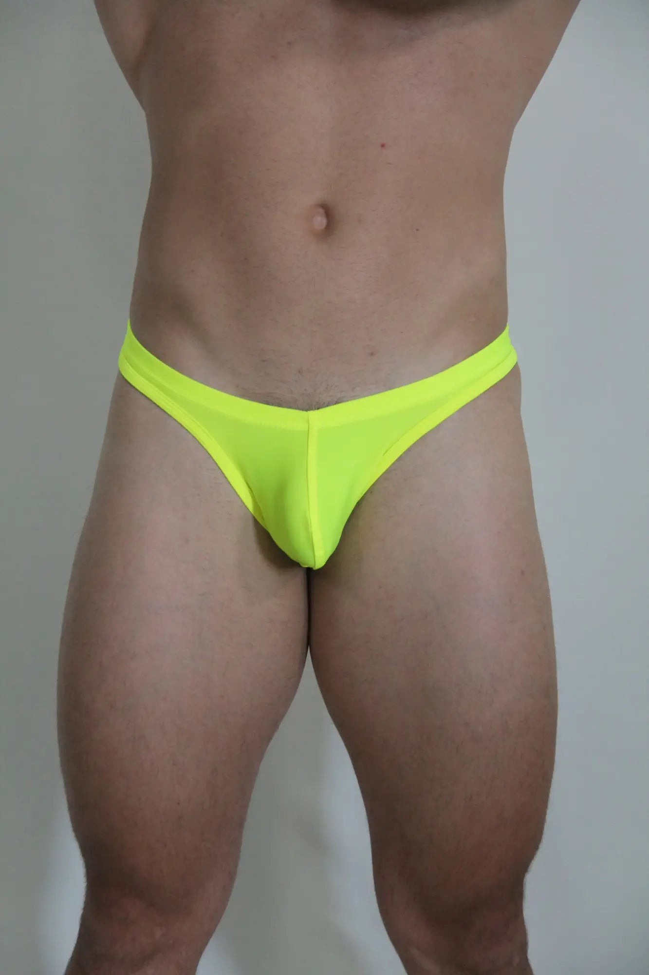Neon yellow swim thong briefs in stretchy fabric shown from the back available in four vibrant colors