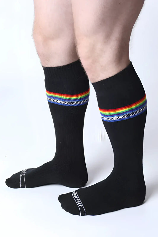 Black pride knee high socks with vibrant rainbow stripe, decorative blue pattern, and white text on the toe area
