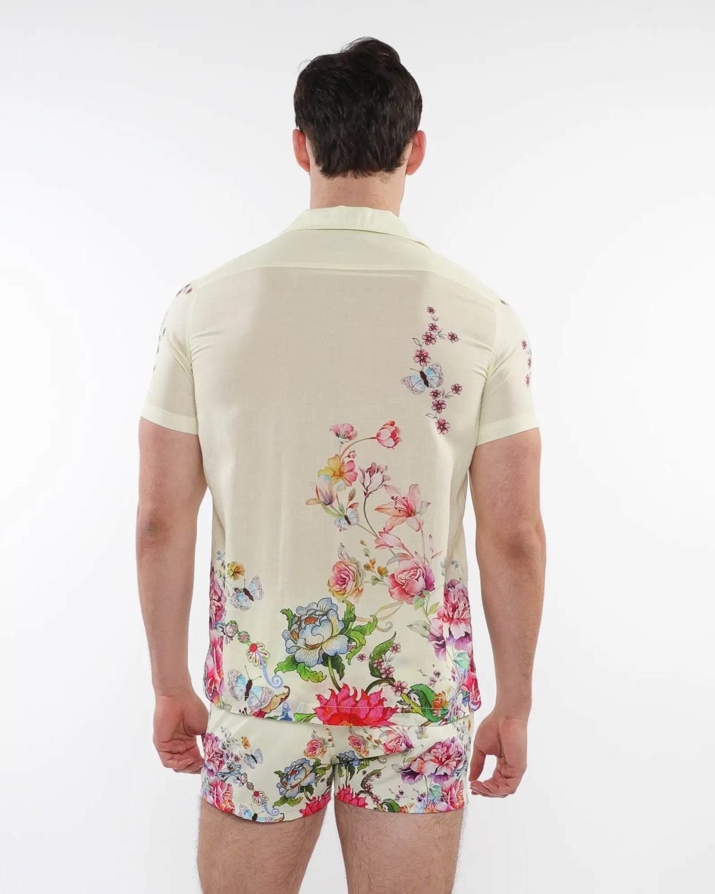 A man wearing a cream printed short-sleeved woven modal border shirt with vibrant floral and butterfly patterns