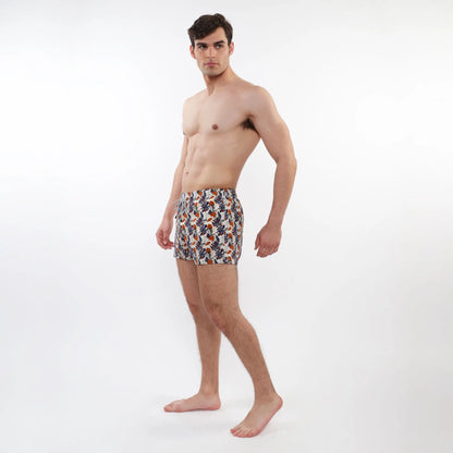 Printed swim short with mesh lining featuring vibrant tropical leaf pattern in orange navy blue and cream on white base