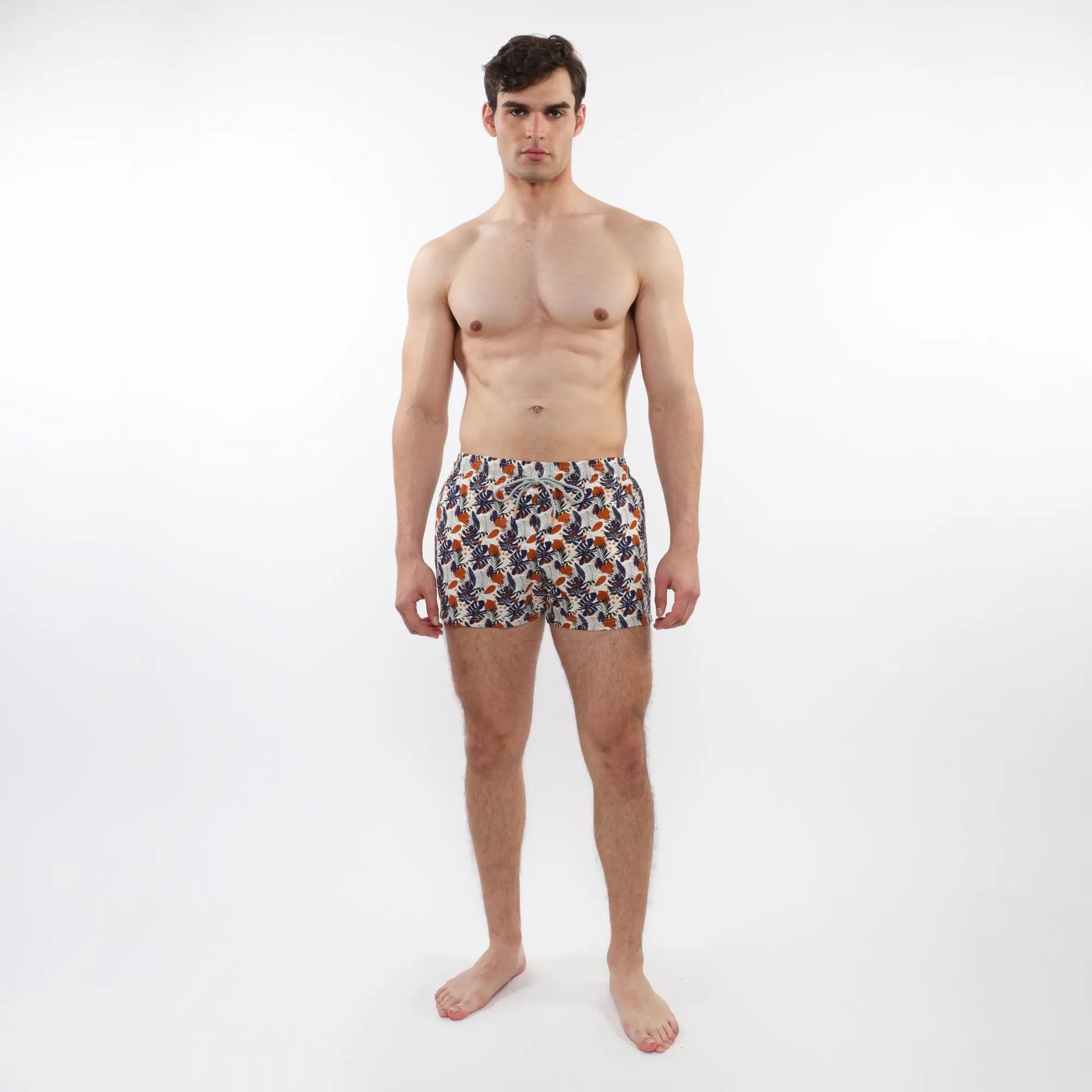 Men’s printed swim short with mesh lining in orange navy blue and white tropical leaf and fruit pattern on light fabric