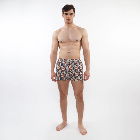 Men’s printed swim short with mesh lining in orange navy blue and white tropical leaf and fruit pattern on light fabric