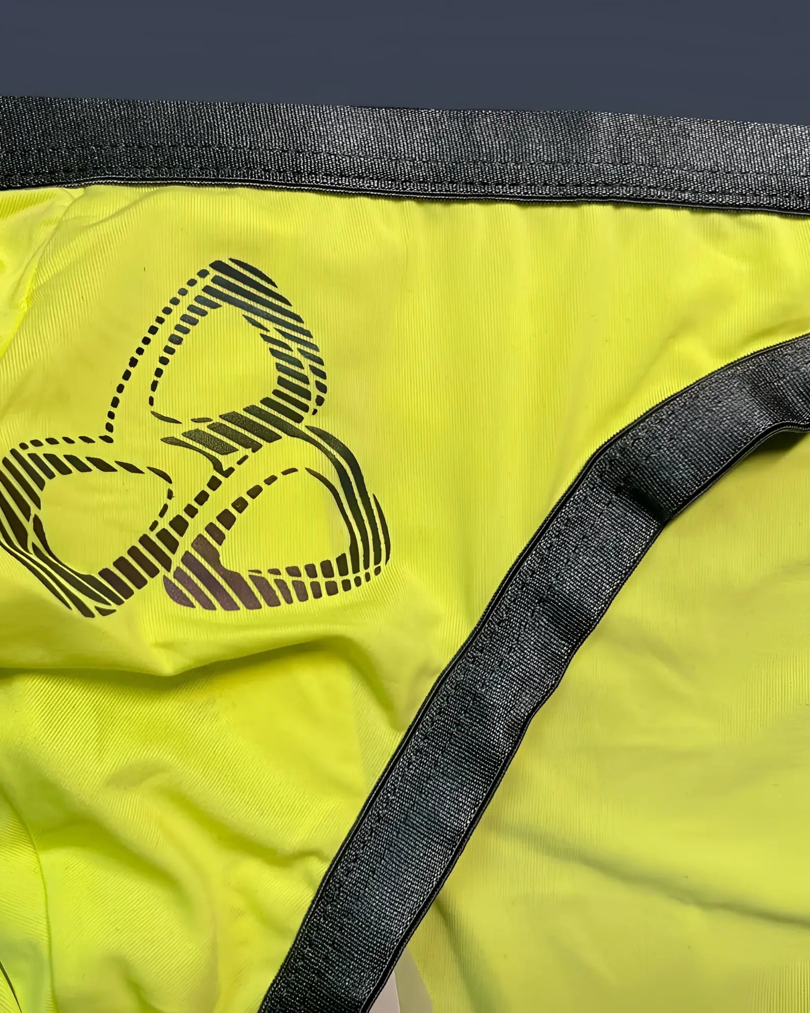 Private Structure BRUT4393 bare bikini briefs in bright yellow with dark gray waistband and black three-leaf logo