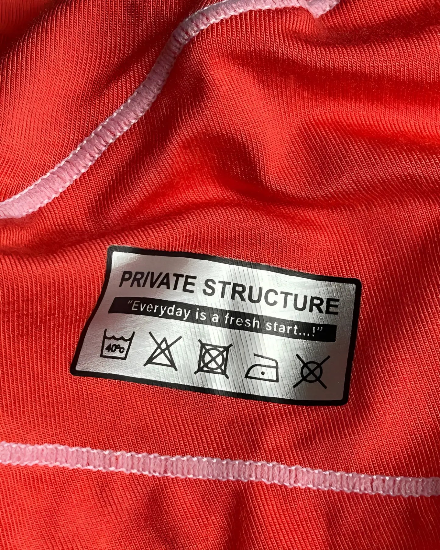 Silver rectangular care label on the back of private structure epus4570 prime elysian hipster in red with laundry instructions