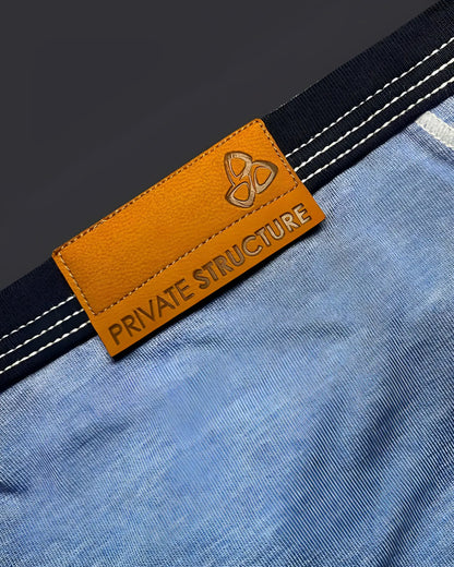 Orange leather brand tag with embossed logo and private structure text on denim fabric of low rise mini brief