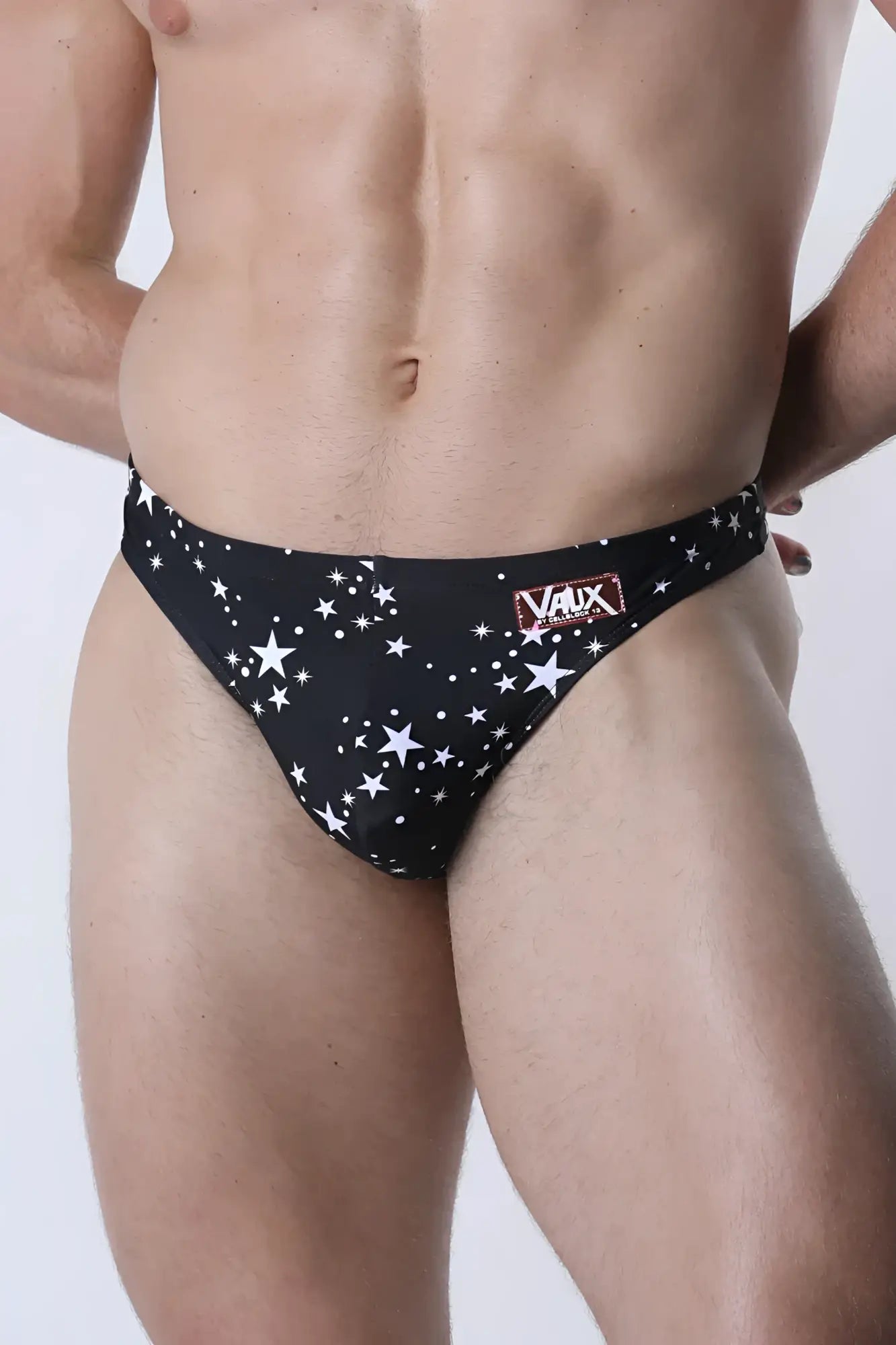 Black star-patterned men’s pulse swim thong briefs with red and white vaux label on the waistband