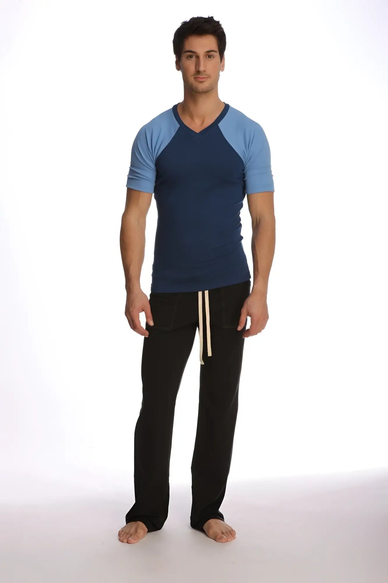 Man wearing a raglan virtual crew neck t-shirt in royal blue with navy and light blue sleeves and black pants with cream drawstrings