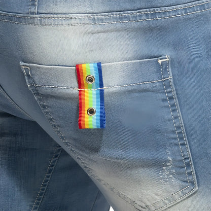 Rainbow tape jean short featuring a rainbow-striped ribbon button with metallic grommets on a denim pocket