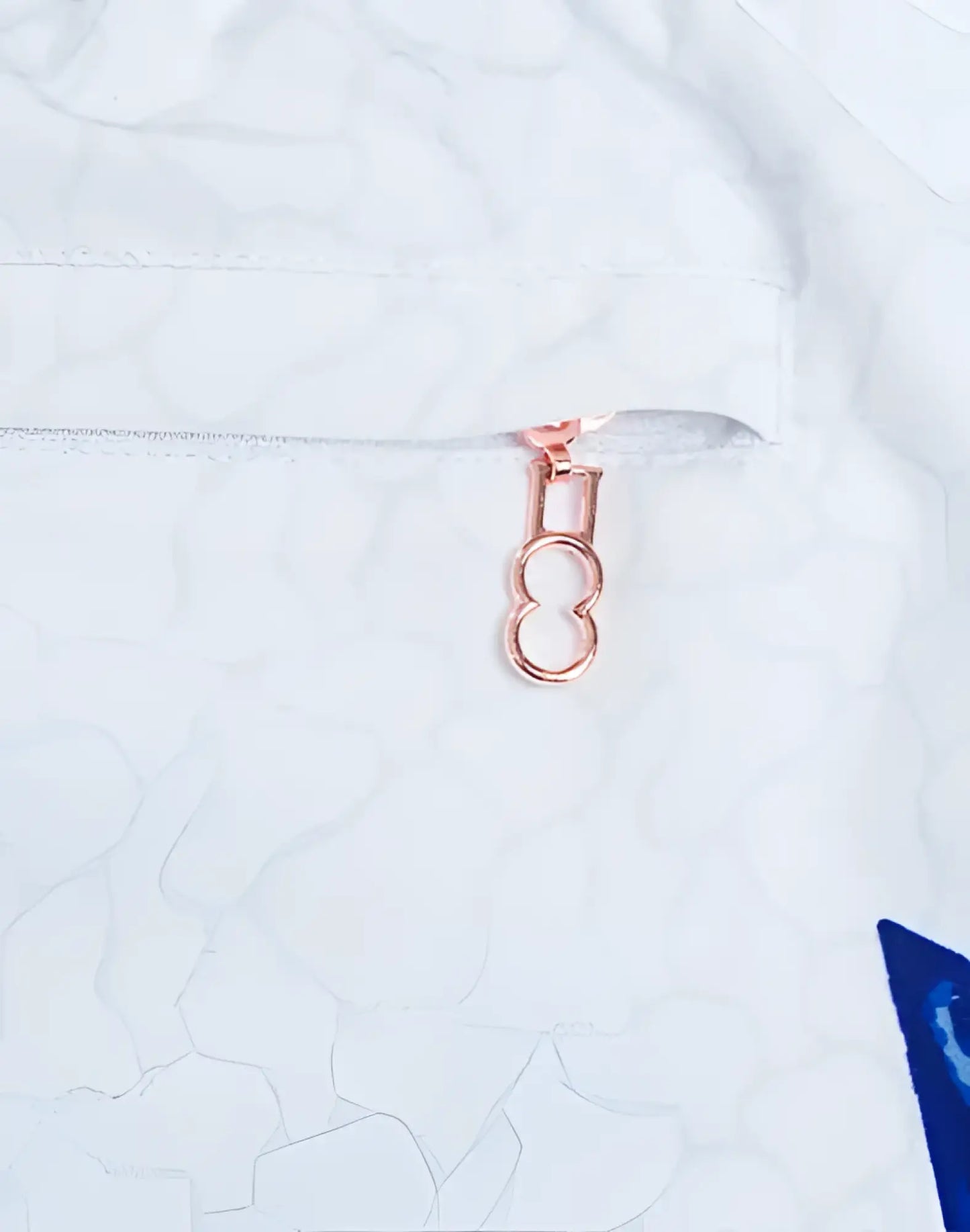 Rose gold zipper pull with figure eight design on white fabric of s50 seascape print swim short