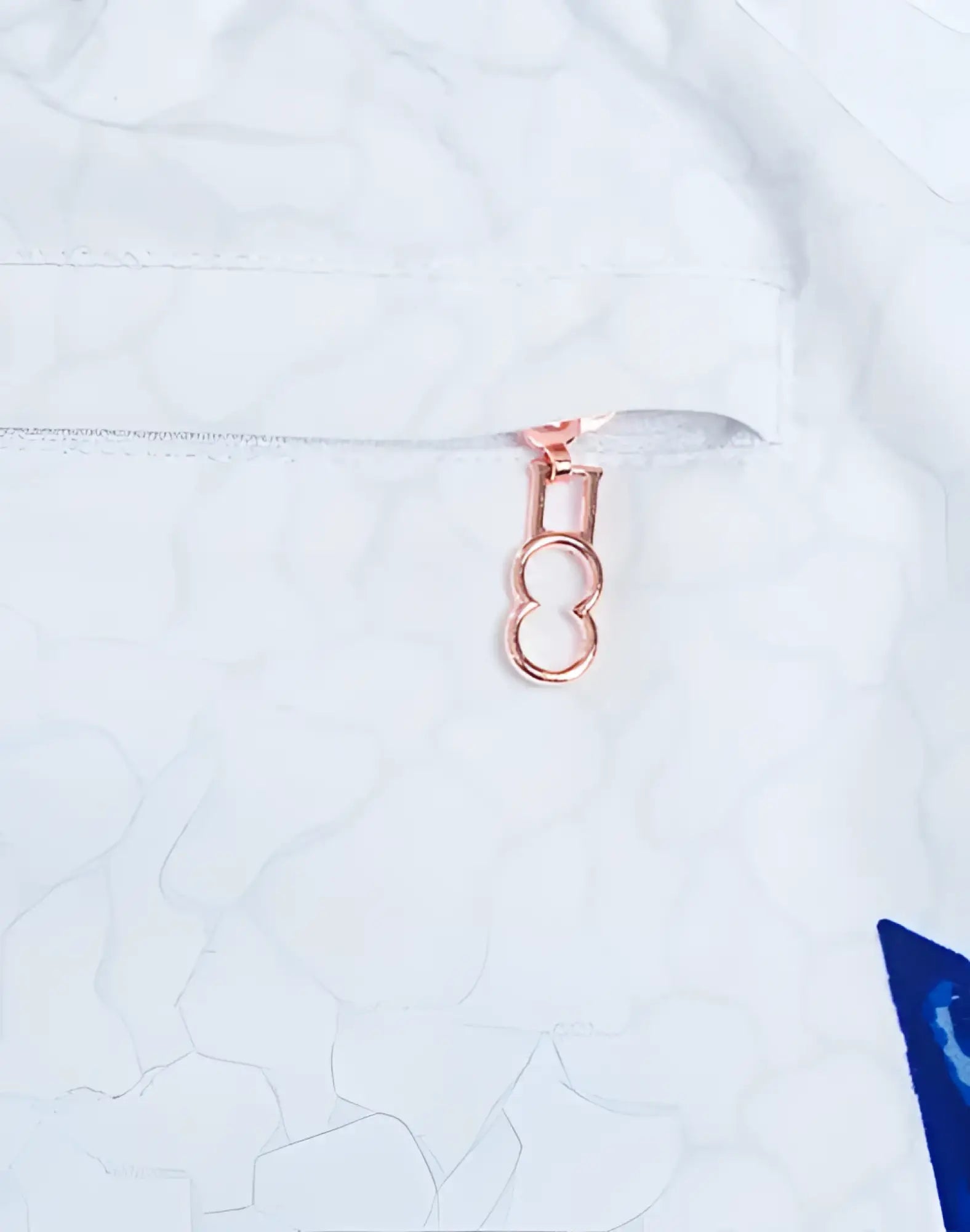 Rose gold zipper pull with figure eight design on white fabric of s50 seascape print swim short