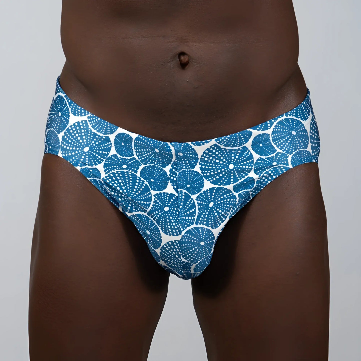 Blue and white patterned sand dollar brief swim trunks featuring a repeating circular dotted motif design