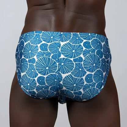 Blue and white patterned sand dollar brief swim trunks featuring circular sea urchin motifs for beachwear