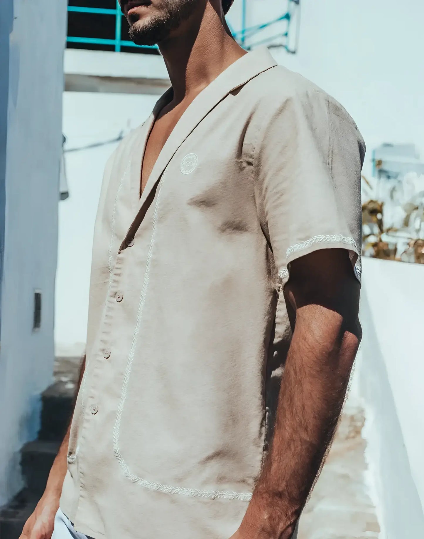 Beige santorini linen shirt with short sleeves and white embroidered trim along the placket and sleeve cuffs