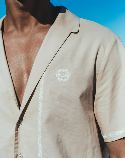 Beige linen santorini shirt with short sleeves white embroidered detailing and circular chest logo