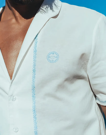 White santorini linen shirt with light blue embroidered detailing on placket and matching logo on chest