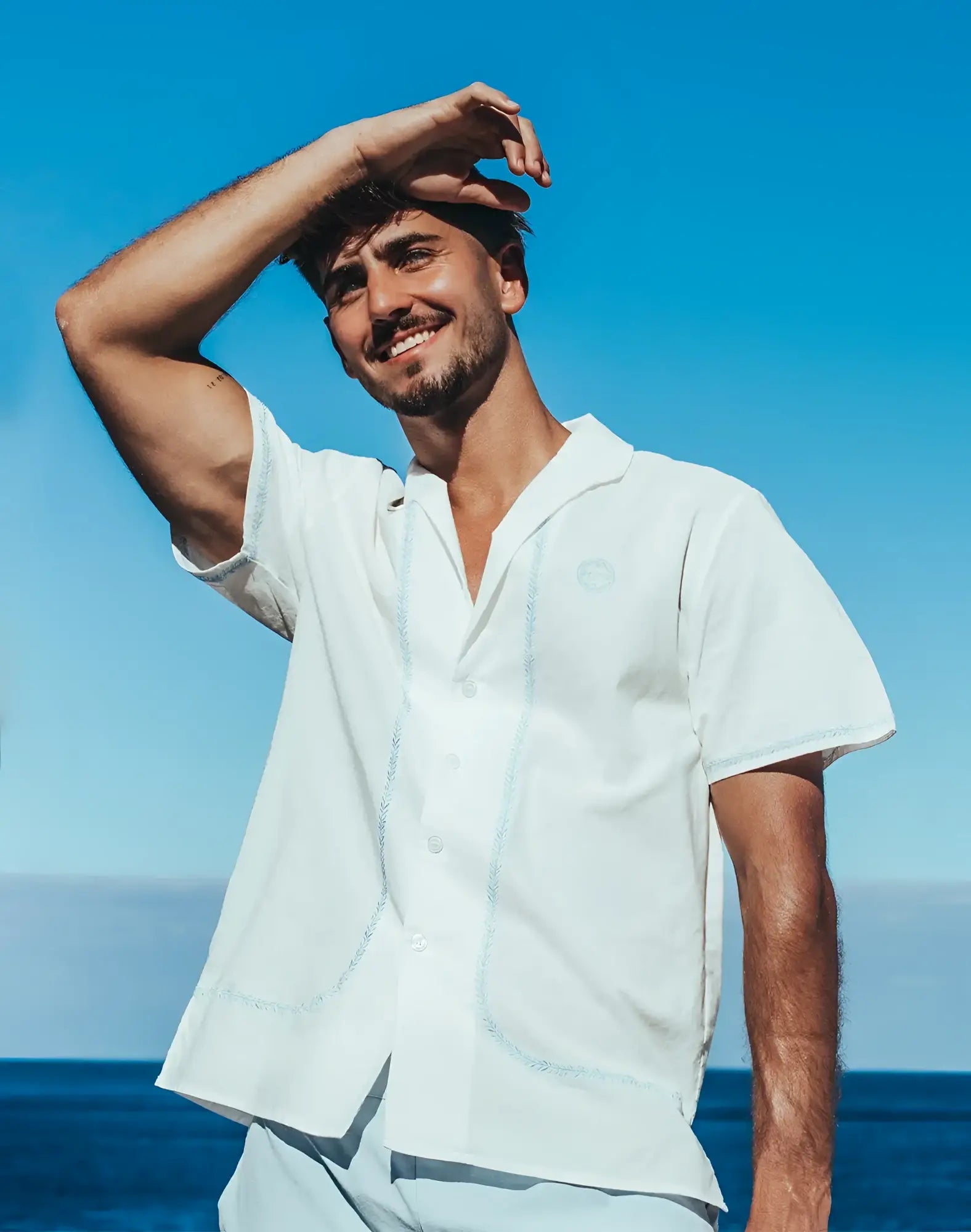 White santorini linen shirt with short sleeves light blue embroidery and small circular logo on left chest