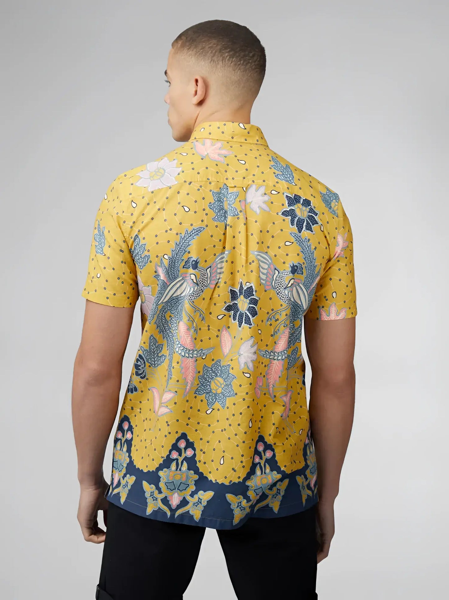 A vibrant yellow short-sleeved shirt with blue and pink floral bird patterns and a navy blue hemband from signature abstract botanical print