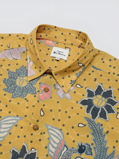 Yellow button-up shirt with signature abstract botanical print featuring vibrant pink blue and gray floral and bird patterns