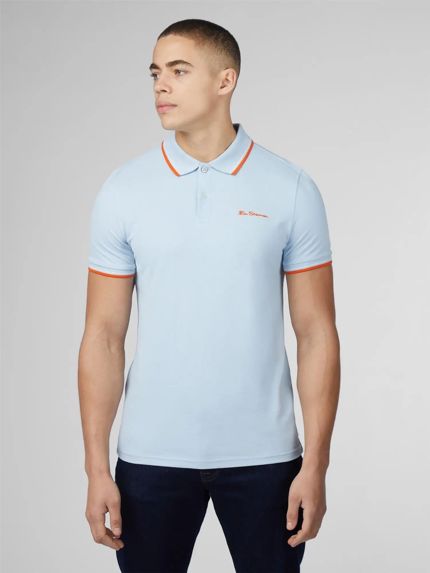 Light blue signature polo shirt with orange collar and sleeve trim featuring a small embroidered chest logo