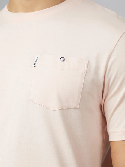 A soft blush pink signature t shirt with short sleeves chest pocket silver button and small branded tag