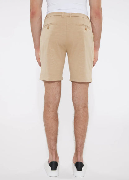 Beige solid stretch knit chino shorts with tailored fit and buttoned back pockets shown from the back side