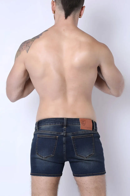 Dark blue denim soma 2.0 booty shorts shown from the back with a brown leather patch on the waistband