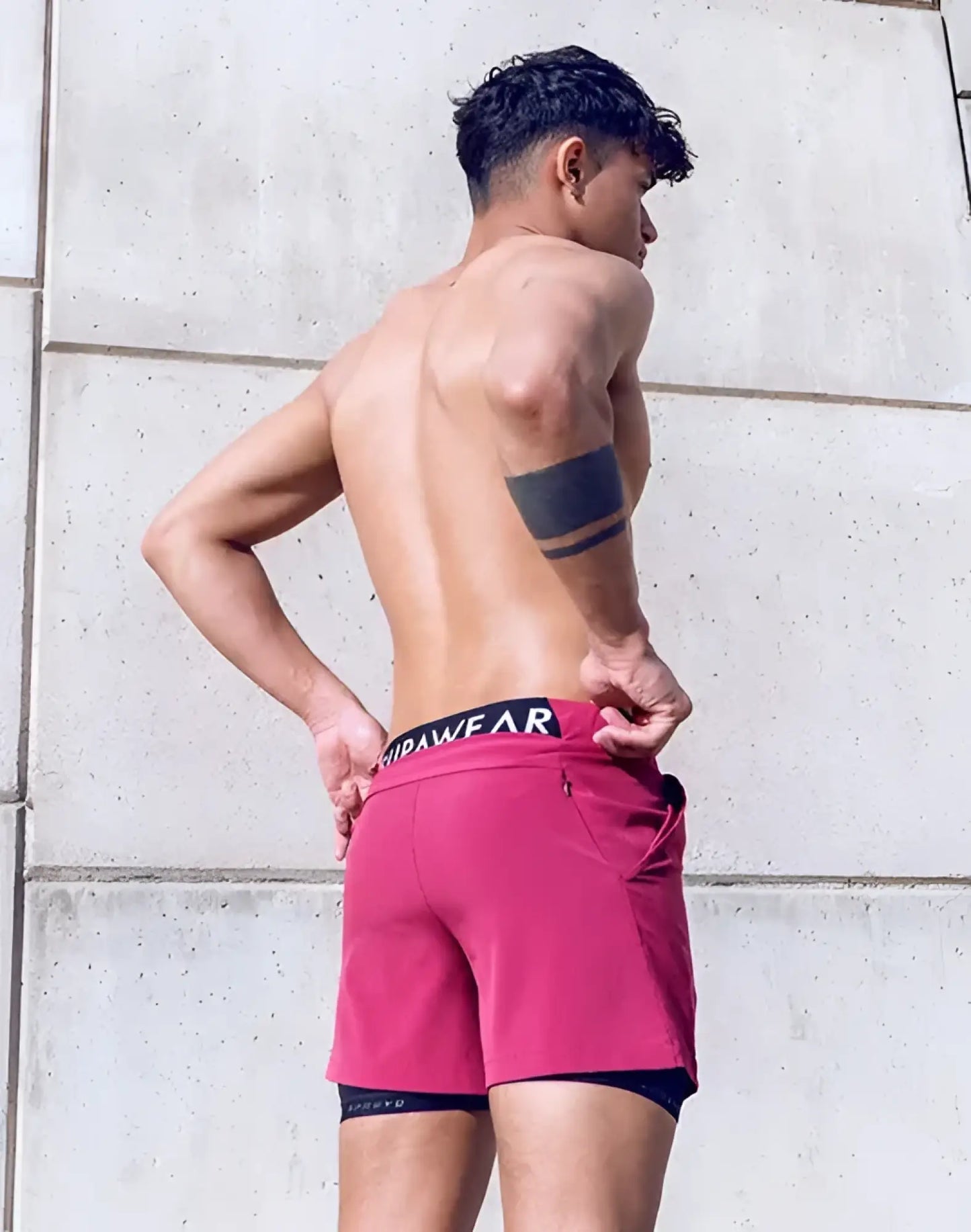 The spr max short features vibrant fuchsia athletic shorts with a black waistband layered over dark blue compression shorts