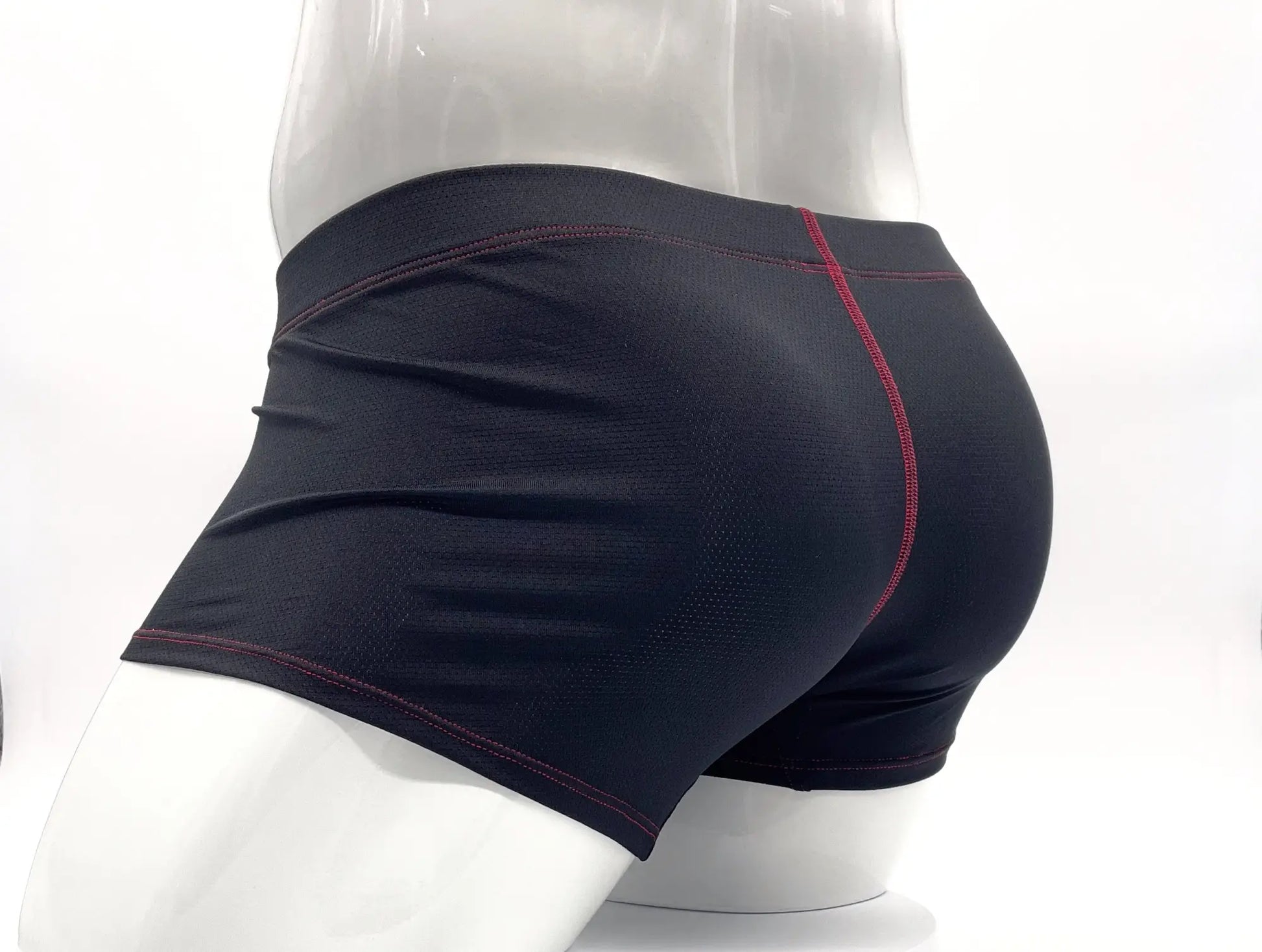 Black athletic boxer briefs with red stitching along seams displayed on mannequin for comfortable support