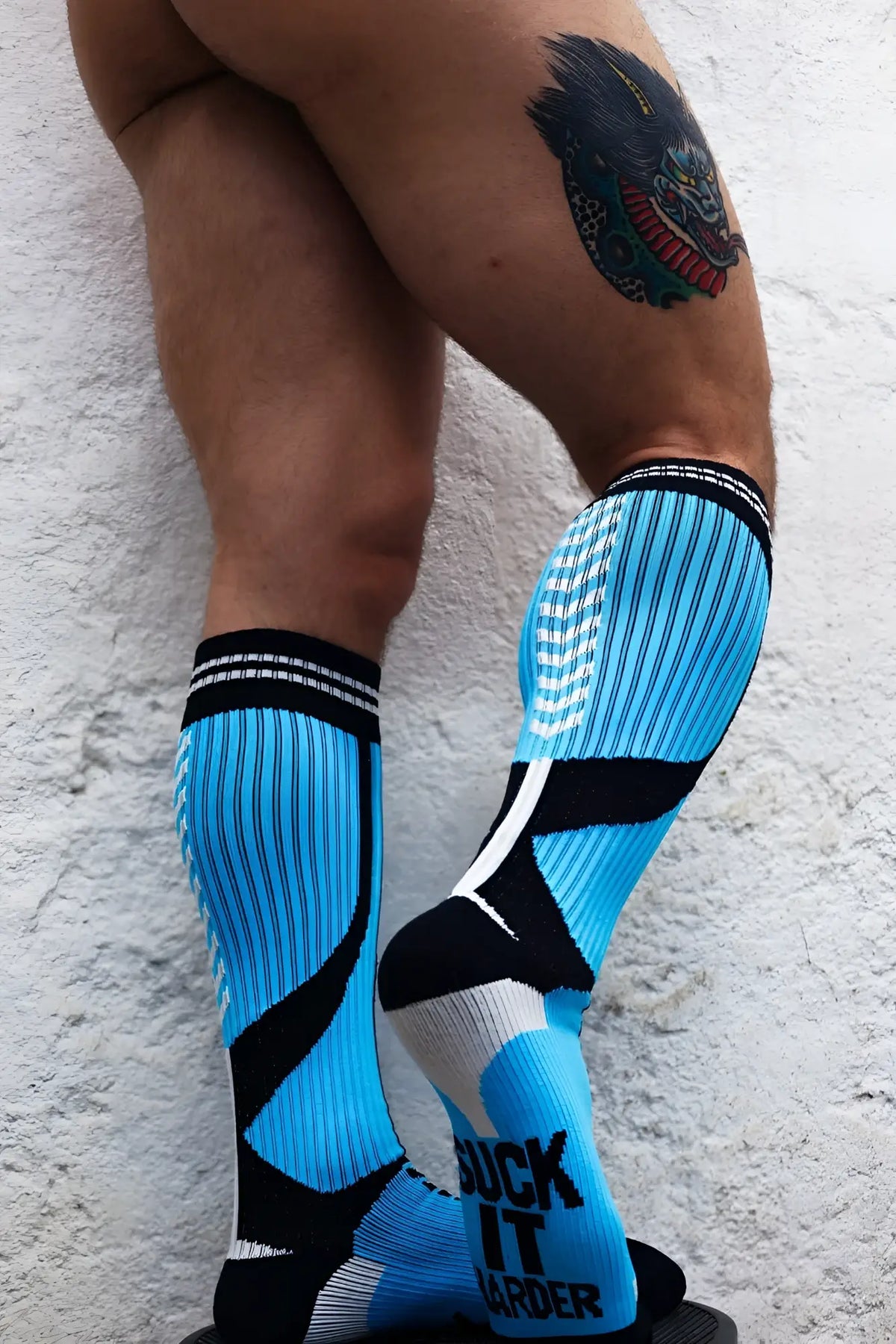 Bright blue and black athletic compression socks with white accents featuring bold suck it harder graphic on foot