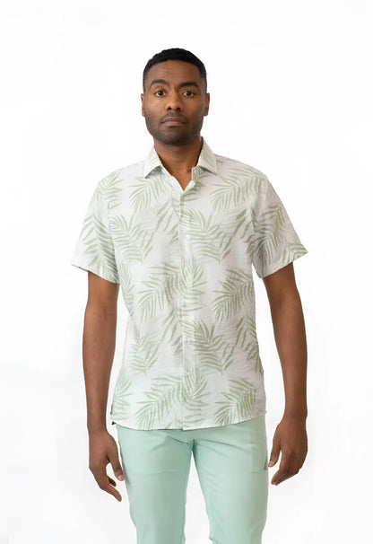 A man wearing a summer rain s s shirt with light green palm leaf pattern on off-white short-sleeved button-up fabric