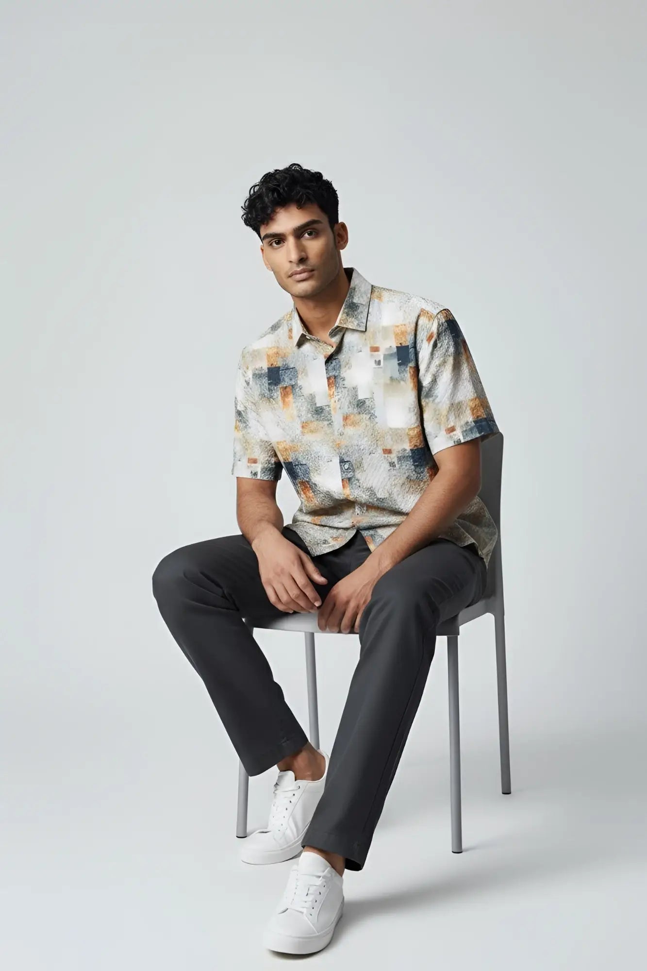 A man wearing a suslo crinkled fabric s s shirt with an abstract geometric pattern in beige gray and orange tones