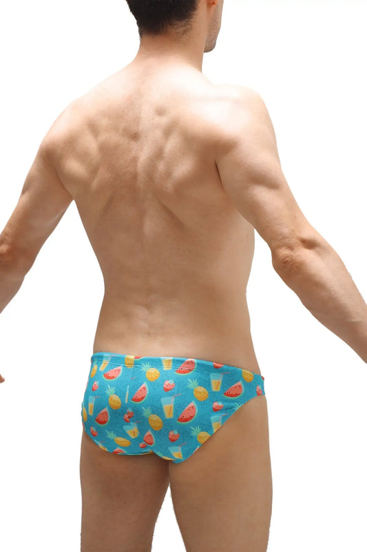 Blue swim bikini taik punta swim trunks with a playful pattern of watermelons pineapples and tropical drinks