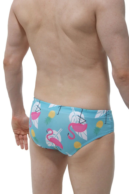 Light blue swim brief pina colada with a male cup pad featuring pink flamingos white tropical leaves and yellow pineapples