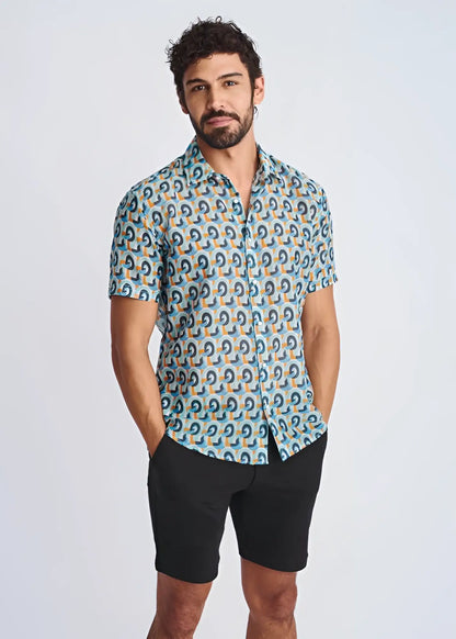 A man wearing a swirls lightweight cotton silk short-sleeved shirt with blue teal and orange geometric pattern