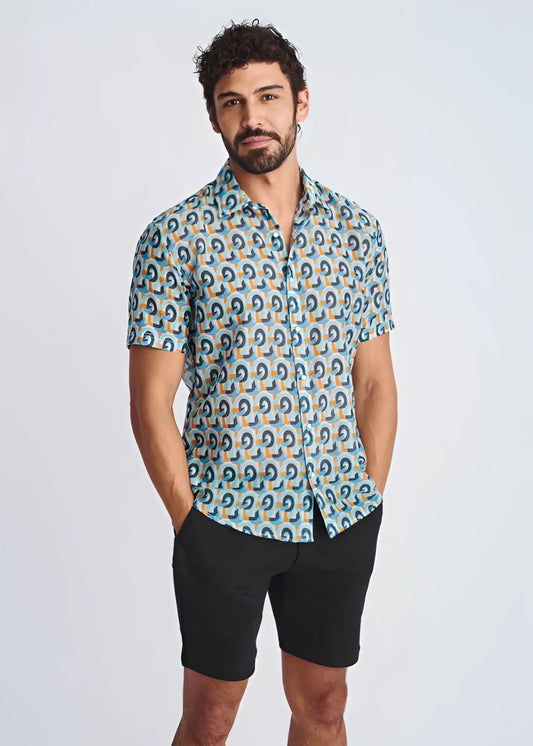 A man wearing a swirls lightweight cotton silk short-sleeved shirt with blue teal and orange geometric pattern