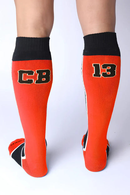 Take down knee high socks in bright orange with black ribbed cuffs toe accents and bold cb 13 lettering outlined in white