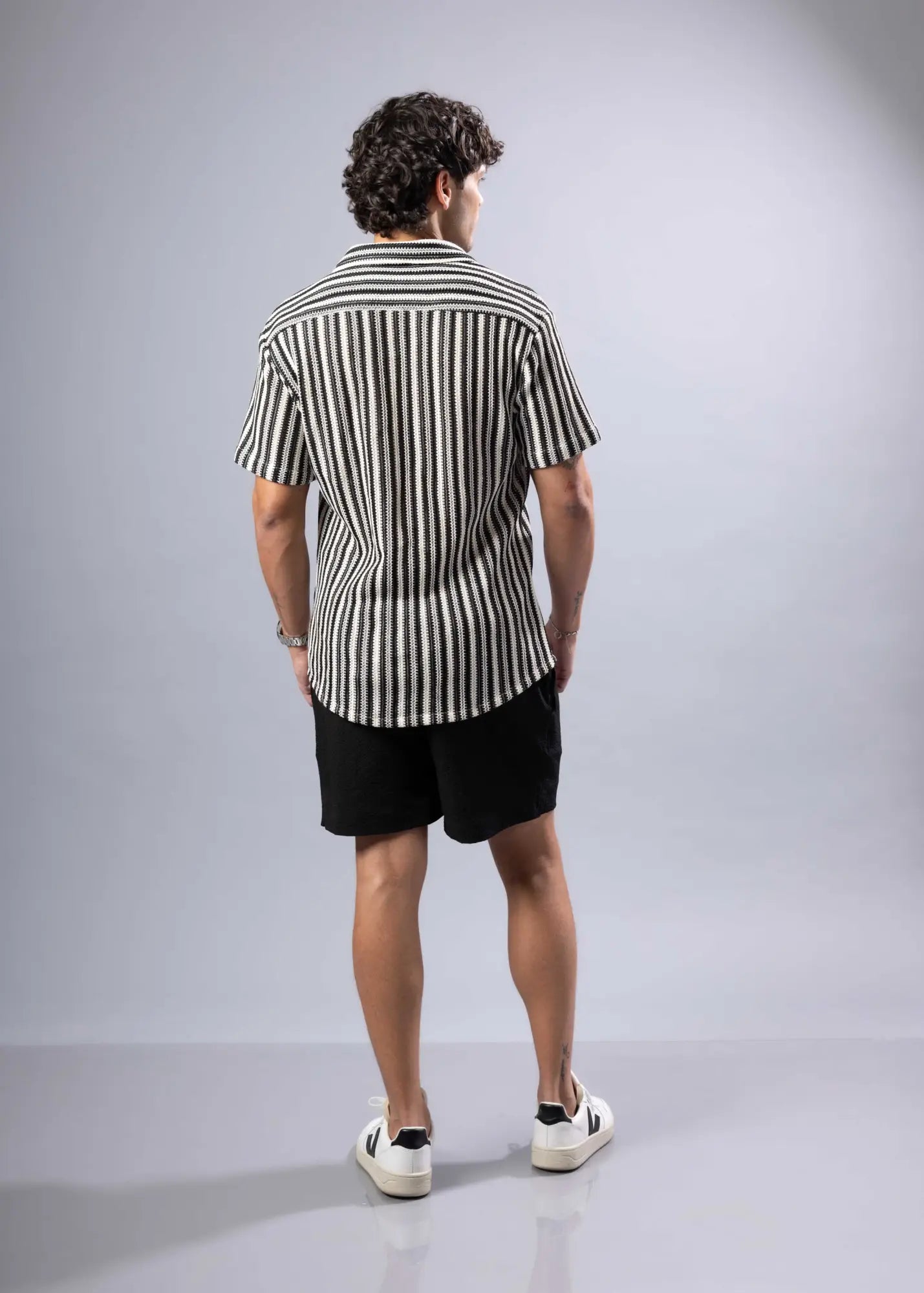 A man wearing a black and white vertically striped texture knit short-sleeved shirt for casual wear