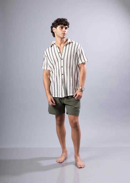 A man wearing a texture knit s s shirt with vertical black and off white stripes in short sleeves