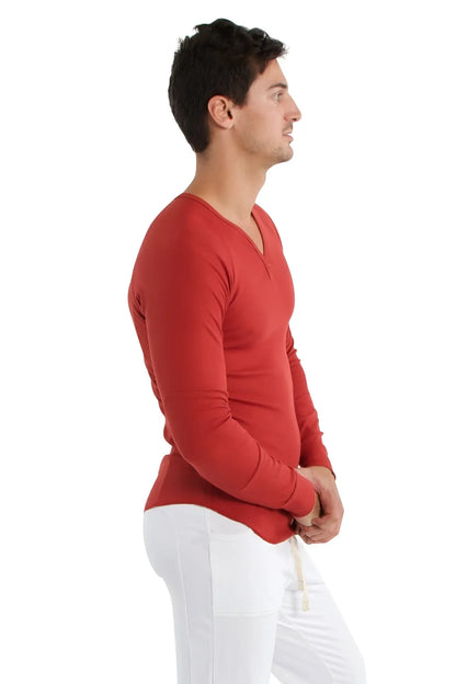 A man wearing a cinnabar thermal v-neck long sleeve shirt made of smooth fabric for warmth and comfort