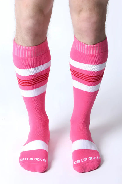 Bright pink tight end knee high socks with white and red stripes featuring cellblock13 logo on the toe