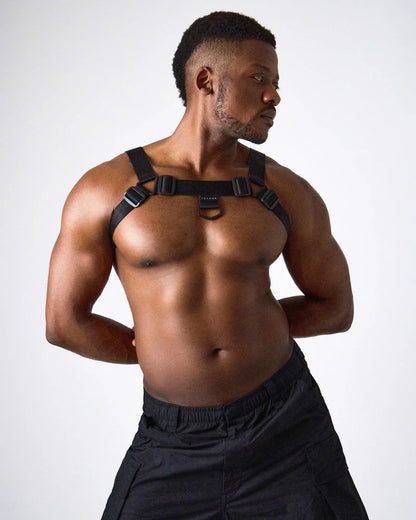 A model wearing a black harness with adjustable straps and a central ring showcasing a muscular physique by teamm8