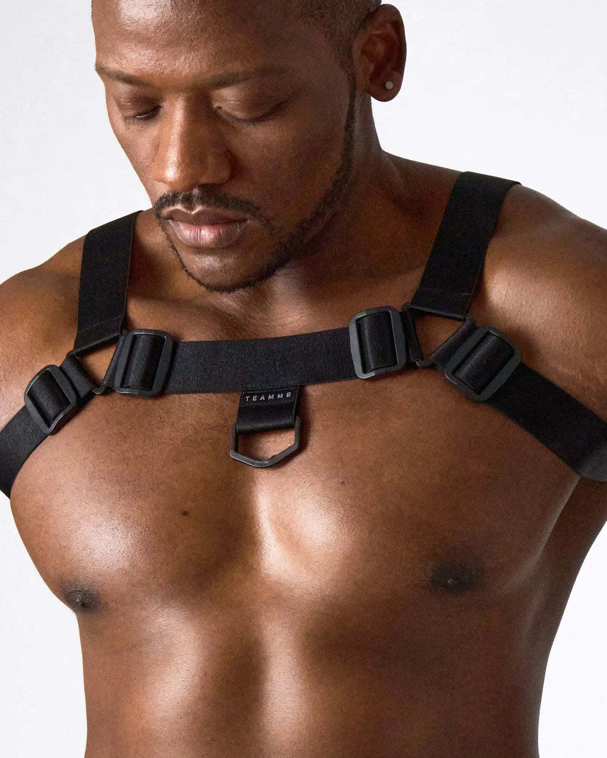 Black harness made of durable material with adjustable straps and metal clips worn by a model from teamm8